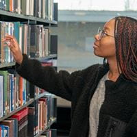 Student selecting a book from a shelf in the library