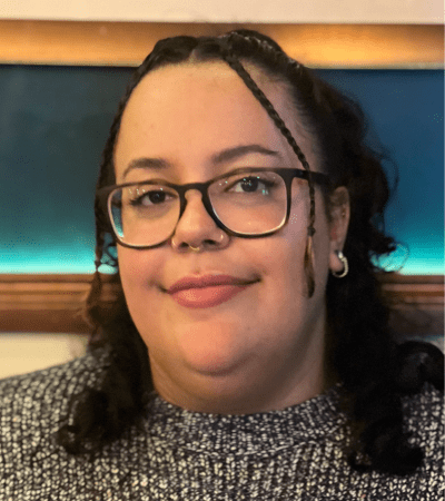A headshot of Rashay, wearing a sweater and glasses.