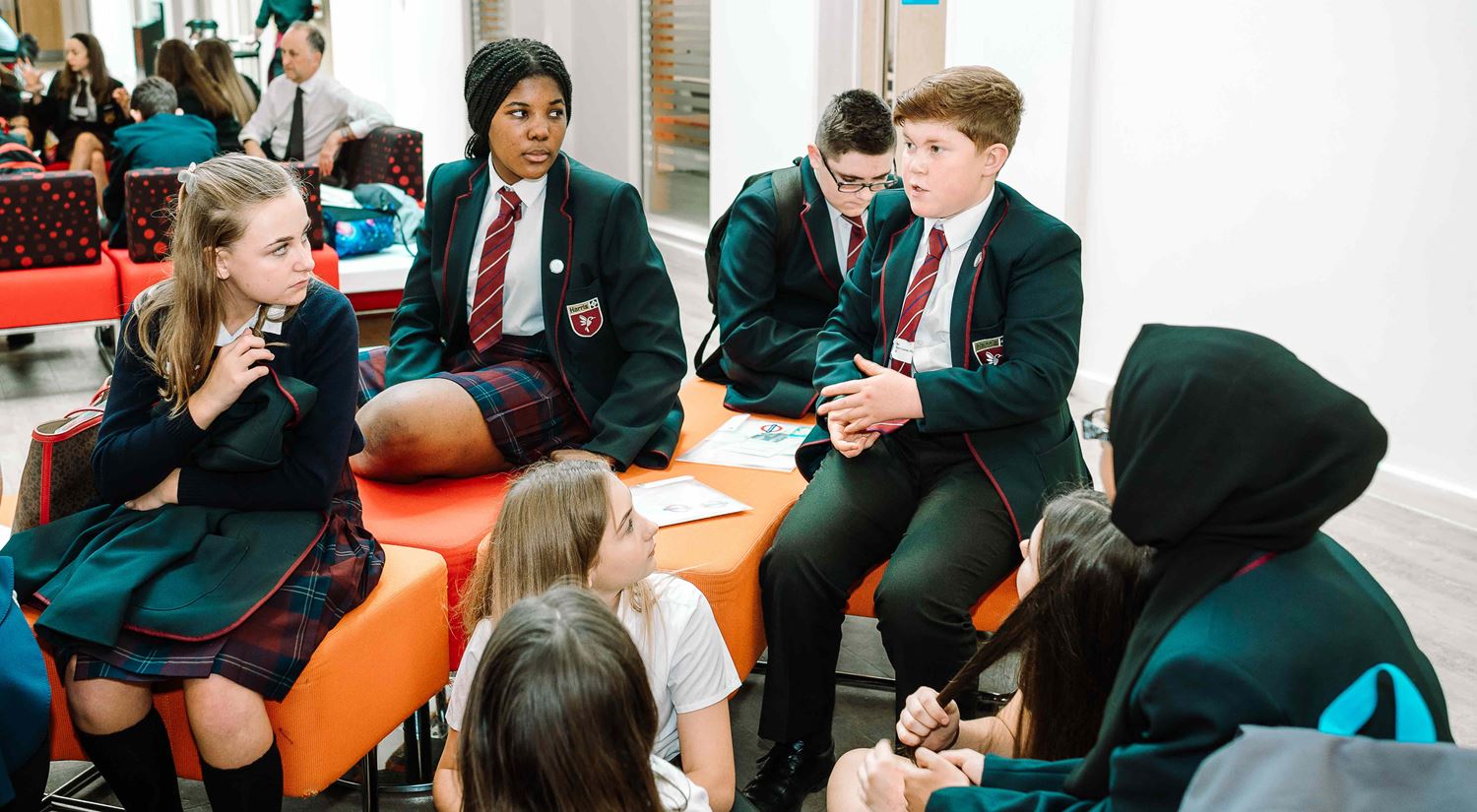 A group of young children, all wearing school uniform, sit together having a discussion